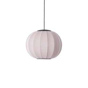 Rund pendellampe i lys pink med stribet overflade, hængt op med sort ledning.